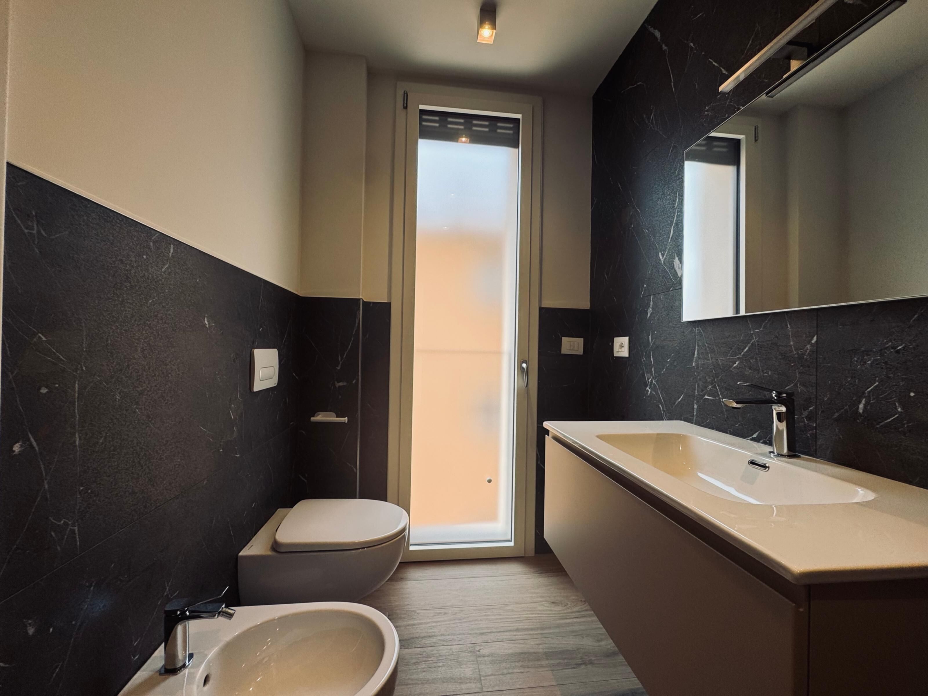 A modern bathroom with a toilet, bidet, and sink.