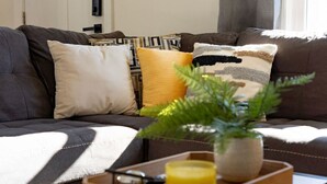 Un salon avec un canapé, une petite table sur laquelle se trouve une plante, une bougie et un plateau.