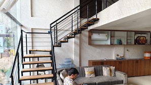 A modern interior with a staircase, a sofa, a coffee table, and a kitchen area. - The Mayfair Hotel (Indore)