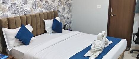 Una cama doble bien hecha, con colcha azul, cabecero de madera y papel tapiz estampado.