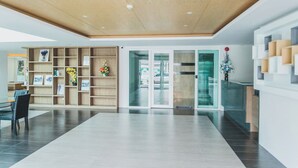 Eine moderne Lobby mit Holzboden, Glastüren und einer Rezeption.