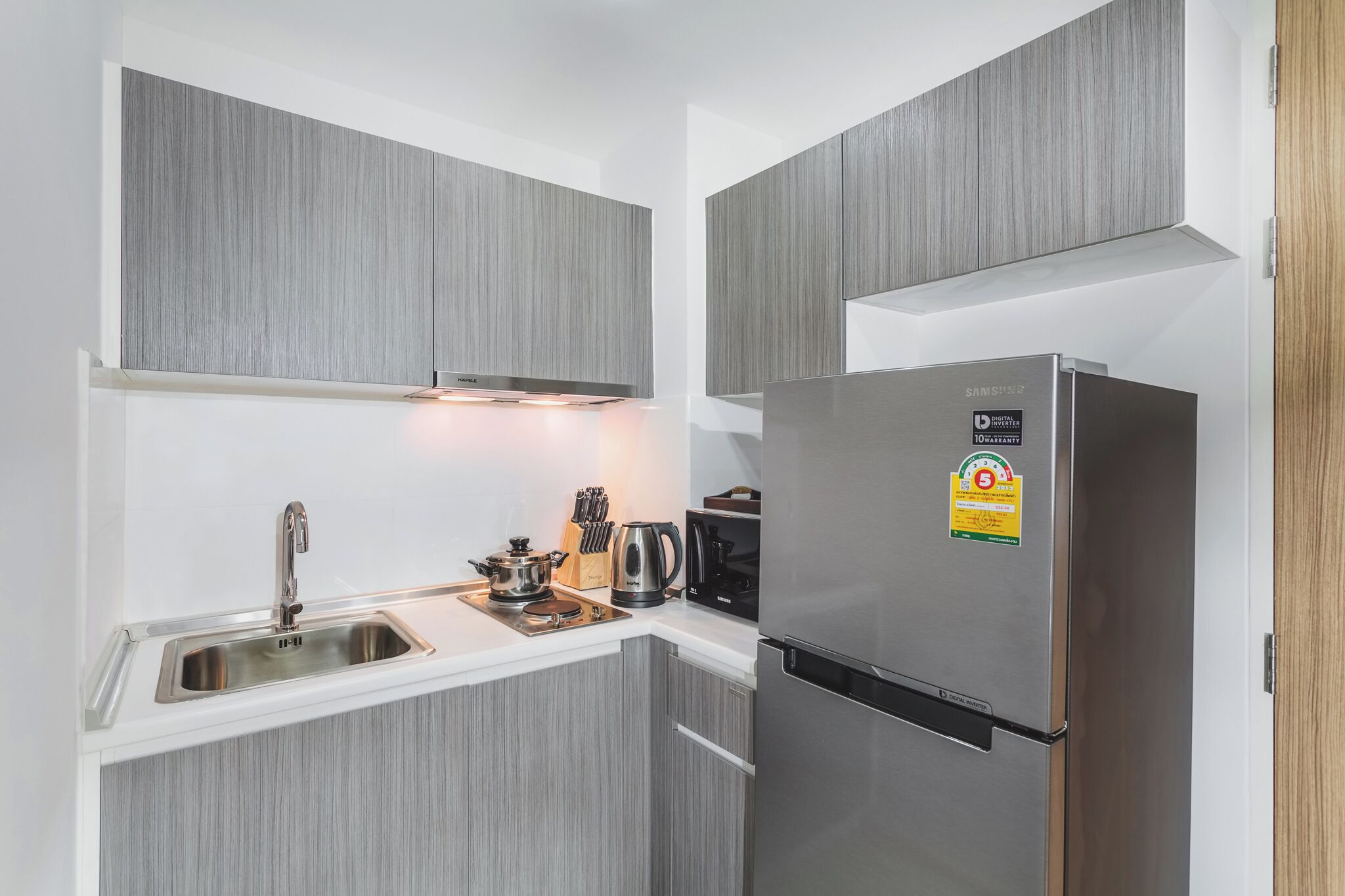 Een moderne keuken met grijze kastjes, een roestvrijstalen spoelbak en een Samsung koelkast.