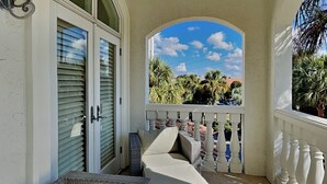 A covered outdoor seating area with wicker furniture and a view of palm trees and a clear sky. - Blue Mountain Bella (Santa Rosa Beach)