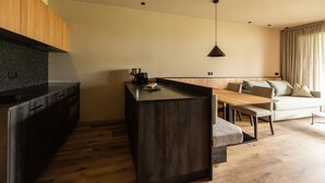 A modern kitchen with dark countertops, a wooden cabinet, and a dining area with a table and chairs. - Apartment 'Oberhaslerhof Floralis' with Mountain View, Wi-Fi and Air Conditioning (Schenna)