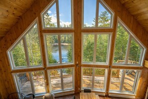 A cabin with large windows offering views of a lake and forest.