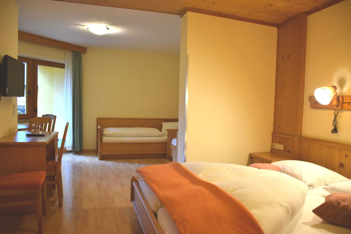 A bedroom with a bed, a desk, and a chair.