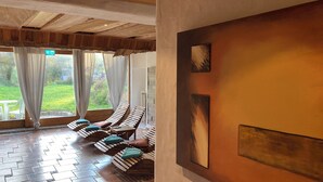 Una habitación con sillas de madera ranurada, suelo de baldosas y vistas a la vegetación.
