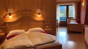 Un dormitorio con paneles de madera, una cama grande, dos mesitas de noche, un revistero, una silla y una ventana con cortinas.