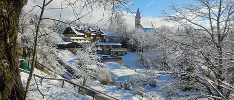 A snow-covered landscape with a large building featuring multiple balconies and a prominent tower.