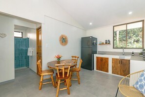 A modern kitchen with a dining area, wooden chairs, a round table, and a refrigerator. - Mística Natural (Playa Conchal)