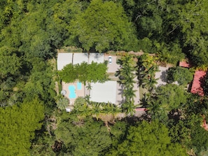 An aerial view of a property with a swimming pool, a covered patio, and surrounding dense vegetation. - Mística Natural (Playa Conchal)