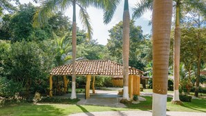 A gazebo with a tiled roof, surrounded by palm trees and lush greenery. - Mística Natural  (Playa Conchal)