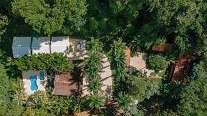 An aerial view of a property with a swimming pool, a covered patio, and dense surrounding vegetation. - Mística Natural  (Playa Conchal)