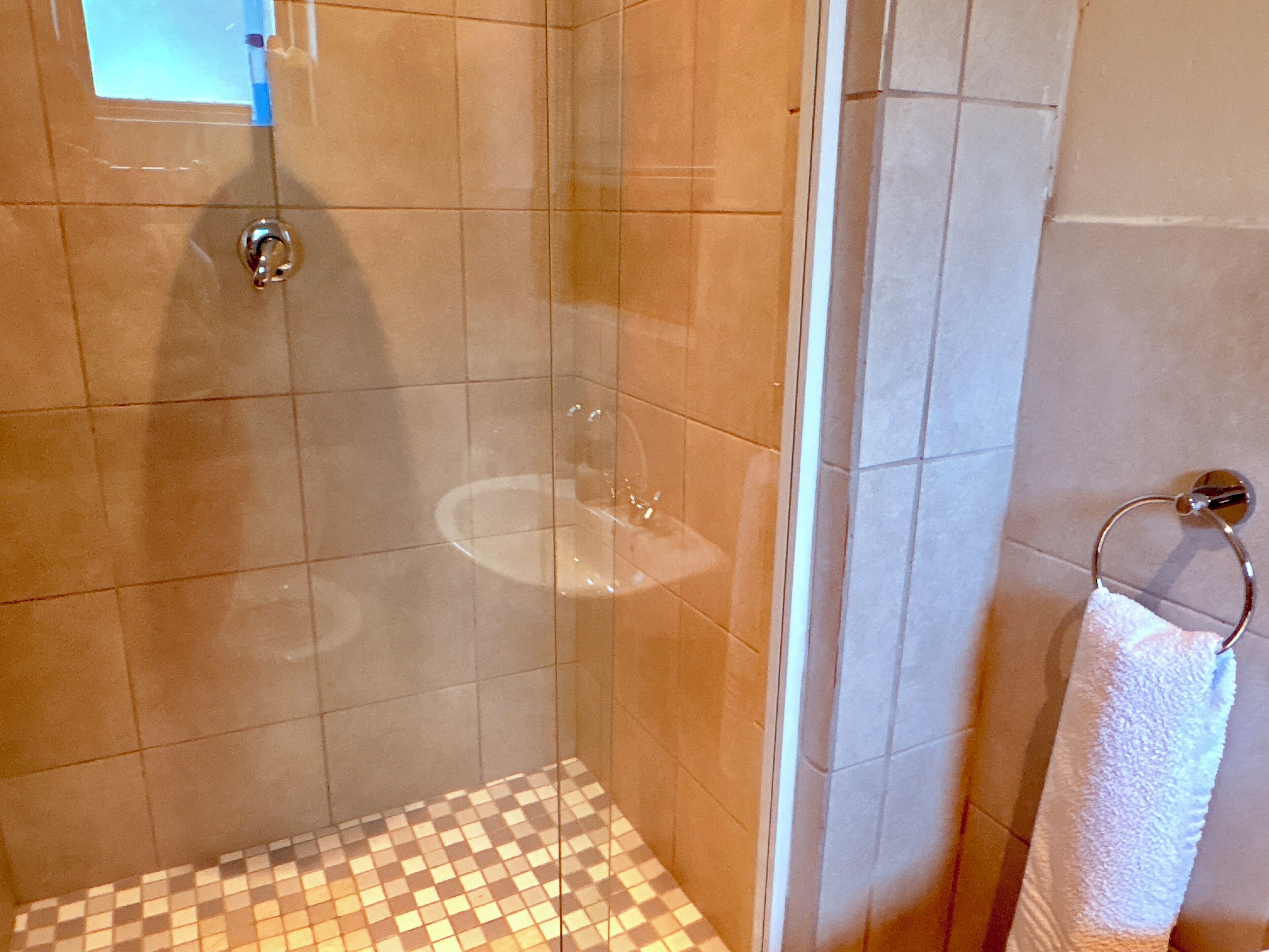 Een douche, handdoeken, zeep, toiletpapier