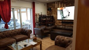 A modern living room with leather sofas, a glass coffee table, and a wooden bookshelf. - Das Gerhards (Wolfhagen)
