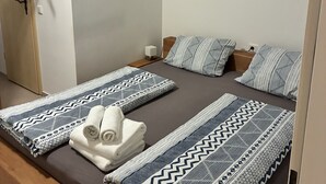 A bedroom with a bed, pillows, a blanket, a towel, a painting, and a wardrobe. - Das Gerhards (Wolfhagen)