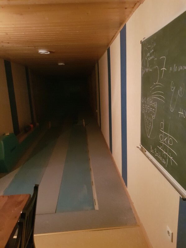 A hallway with a blue and white floor, a blackboard with mathematical equations, and a wooden ceiling.