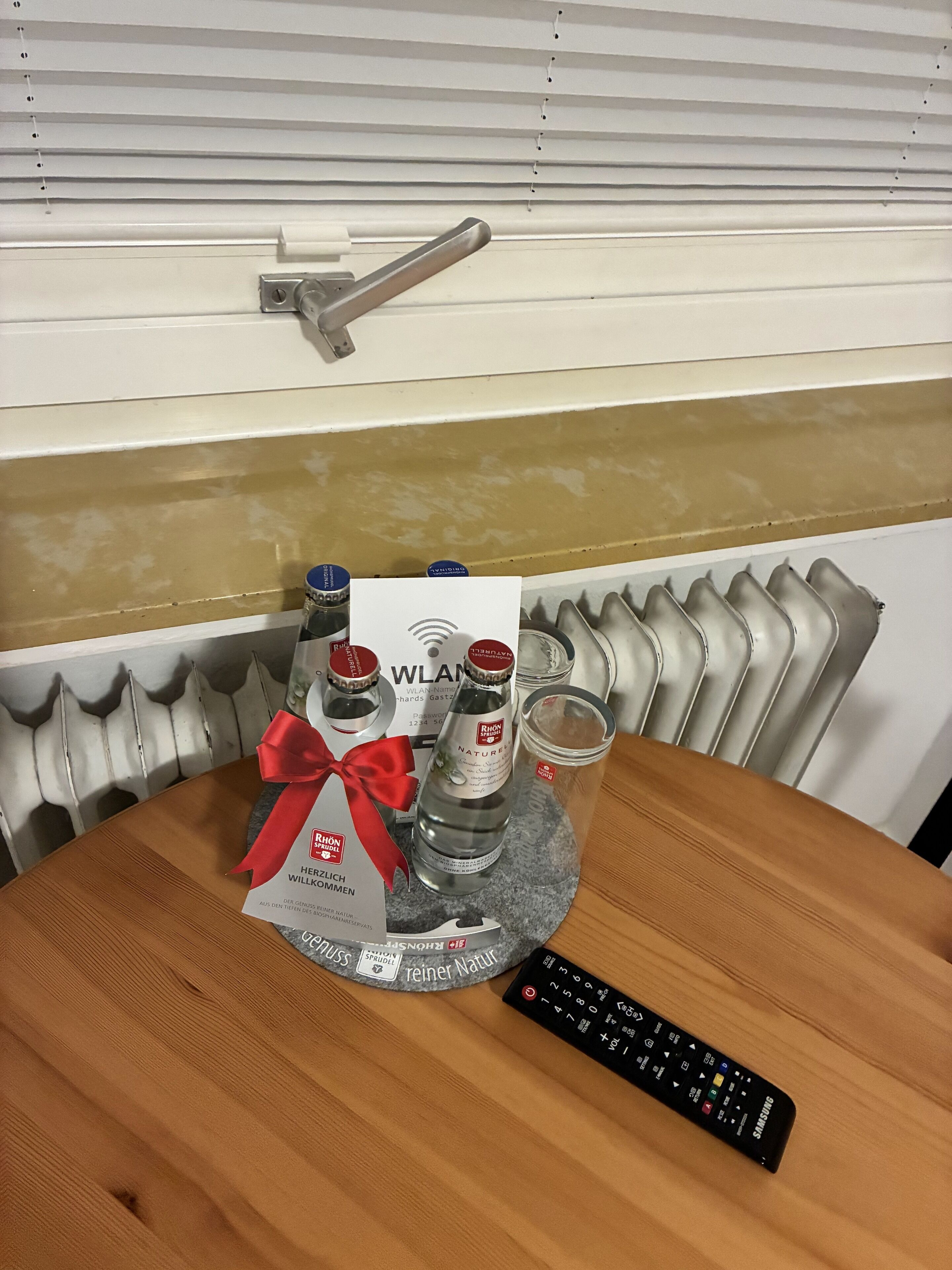 A table with a tray holding bottles, a remote control, and a card.