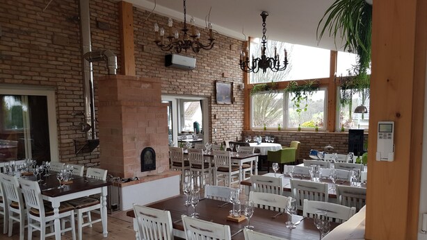 A restaurant with brick walls, wooden furniture, and a brick fireplace. - Das Gerhards (Wolfhagen)