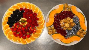 Two plates of assorted fruits and vegetables arranged on a metallic surface. - Das Gerhards (Wolfhagen)