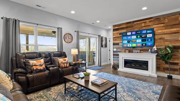 A modern living room with a leather sofa, a coffee table, and a flat-screen TV mounted on a wooden wall.