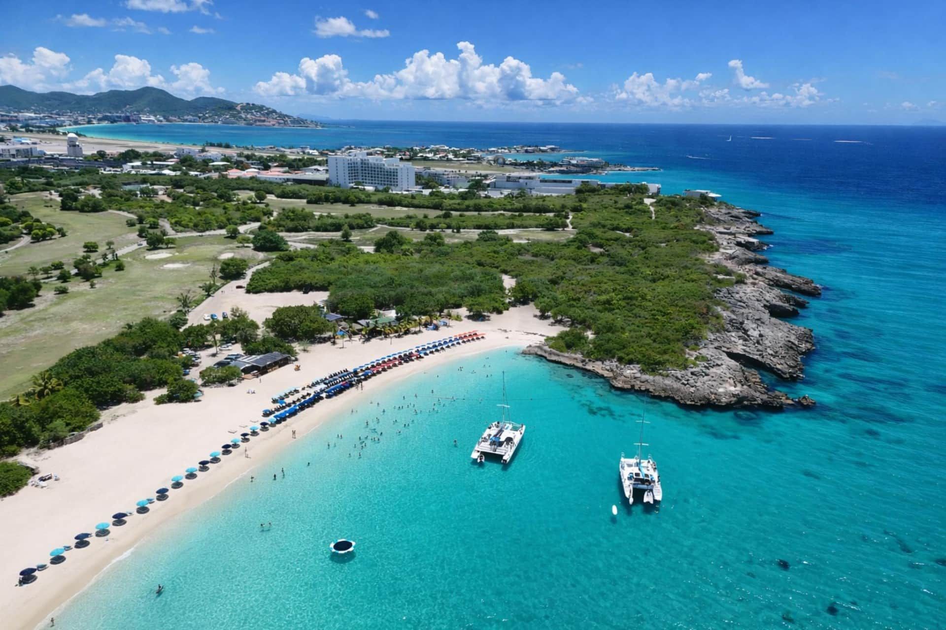An aerial view of a coastal area with a beach, boats, and buildings.