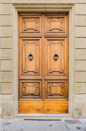 A double wooden door with a classic design, set within a stone wall.