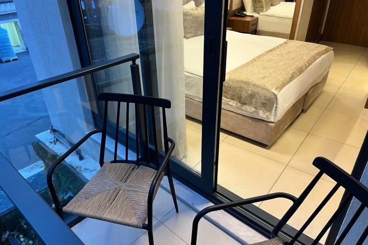 A room with a bed, a chair, and a glass door leading outside.