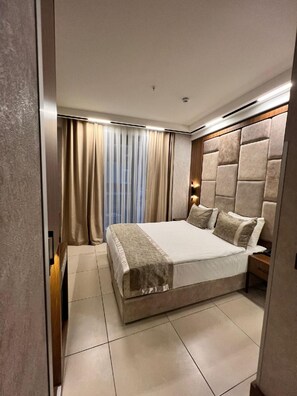 Een moderne slaapkamer met een groot bed, een hoofdeinde en een nachtkastje.