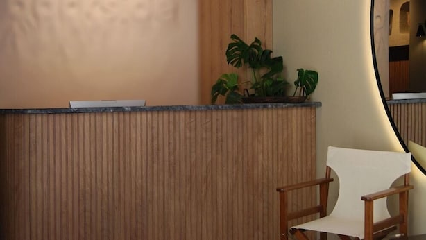 Un comptoir d’accueil avec un revêtement en bois, une plante en pot et un miroir au mur.