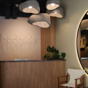 Un comptoir d’accueil avec un revêtement en bois, une plante en pot et un miroir au mur.