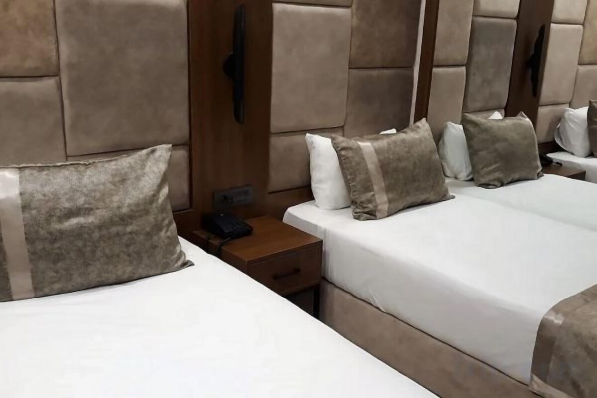 A hotel room with two beds, each with a wooden headboard, a bedside table, and a telephone.
