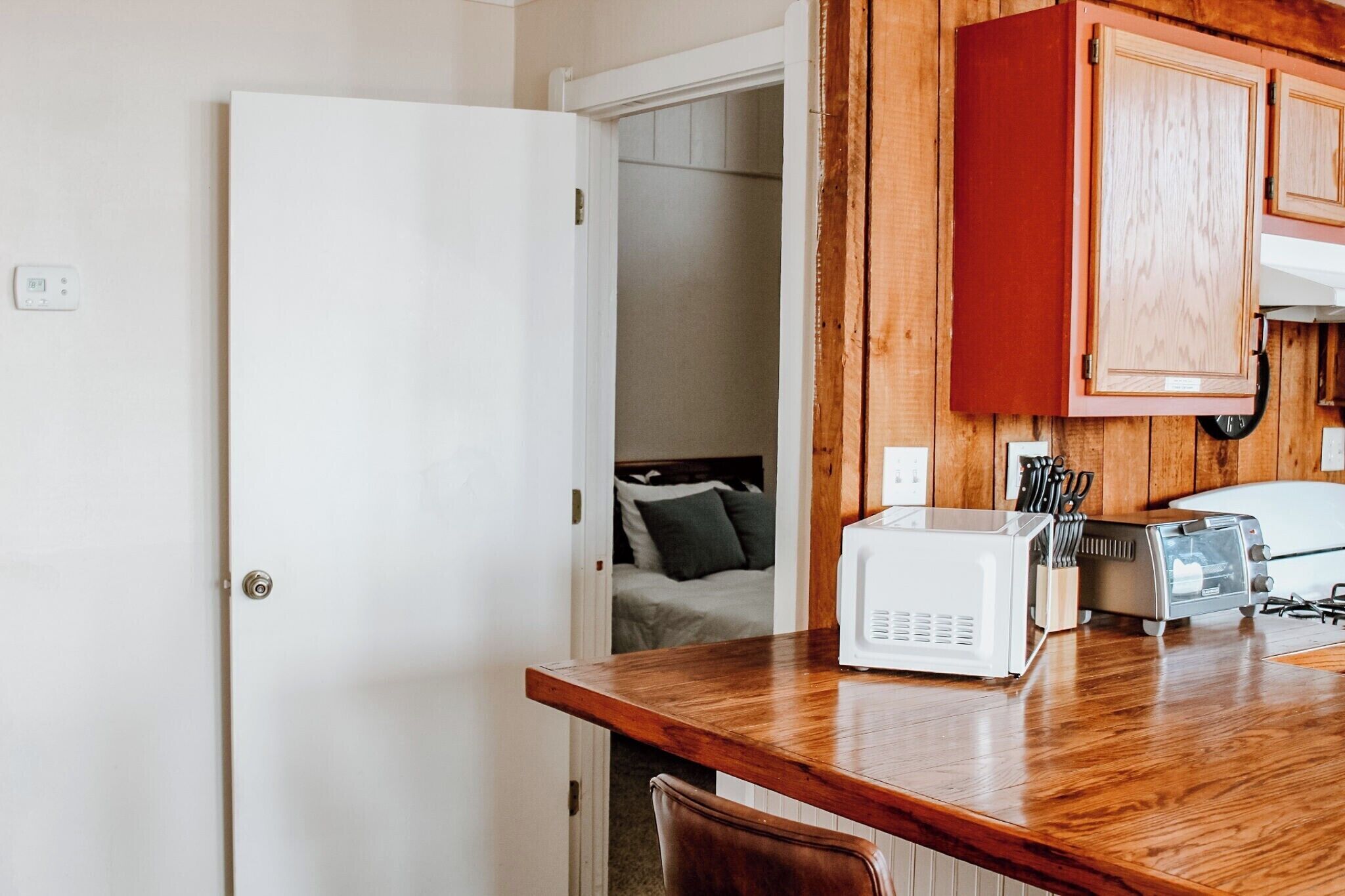 Une cuisine compacte équipée d’un four à micro-ondes, d’un grille-pain et de meubles de rangement en bois.