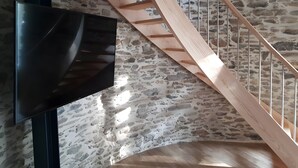 Eine Wendeltreppe mit Steinwand im Hintergrund und einem an der Wand befestigten Flachbildfernseher.