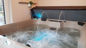 Ein Whirlpool mit Wasserstrahlmassagen, einer Bedienkonsole und Blumentöpfen an der Wand.