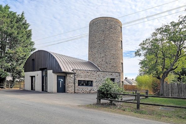 A building with a stone tower and a metal-roofed barn.