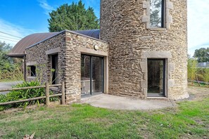 Ein Steinhaus mit einem kleinen Anbau, einem Holzzaun und einer Rasenfläche.