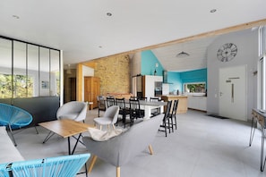 A modern interior with a dining area, kitchen, and a view of the outdoors.