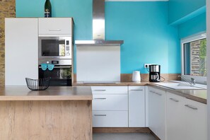 A modern kitchen with white cabinets, a stainless steel oven, and a coffee maker on the counter.