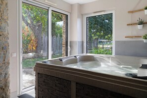 A bathroom with a hot tub, large windows, and a view of the outdoors. - Gîte du moulin de la violaye – Unique Restored Windmill near Nantes (Fay-de-Bretagne)