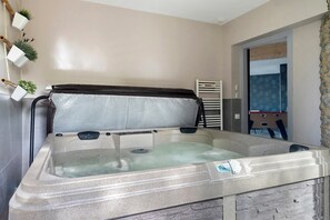 Ein Whirlpool mit einer Holzbank, einer kleinen Pflanze und einem Wandheizkörper.