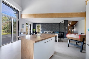 A modern kitchen with a wooden countertop, a dining area with chairs, and a foosball table.