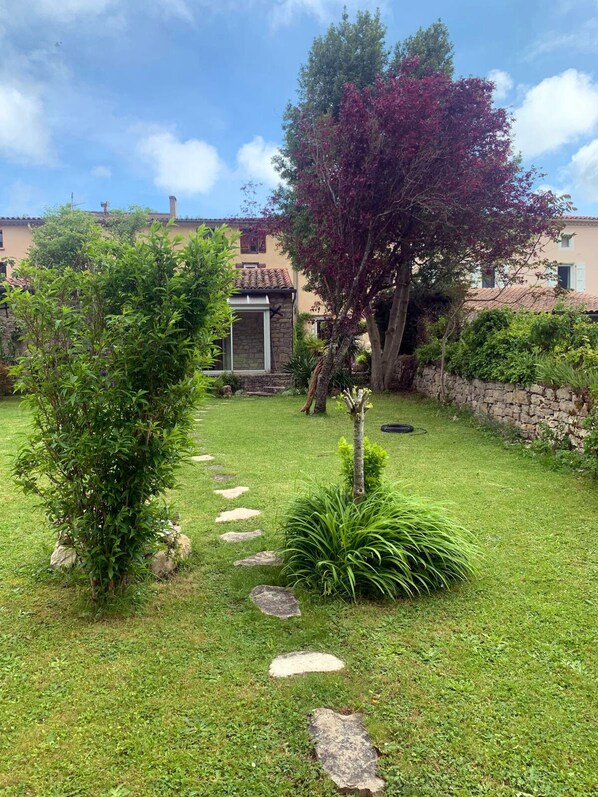 A well-maintained garden with a stone pathway leading to a stone building with a tiled roof.