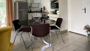 Een moderne keuken met witte kasten, een eettafel met stoelen en een groot raam met gordijnen.