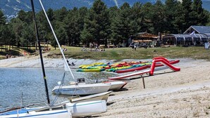 Une zone au bord d’un lac, avec des bateaux, une plage et des montagnes en arrière-plan.