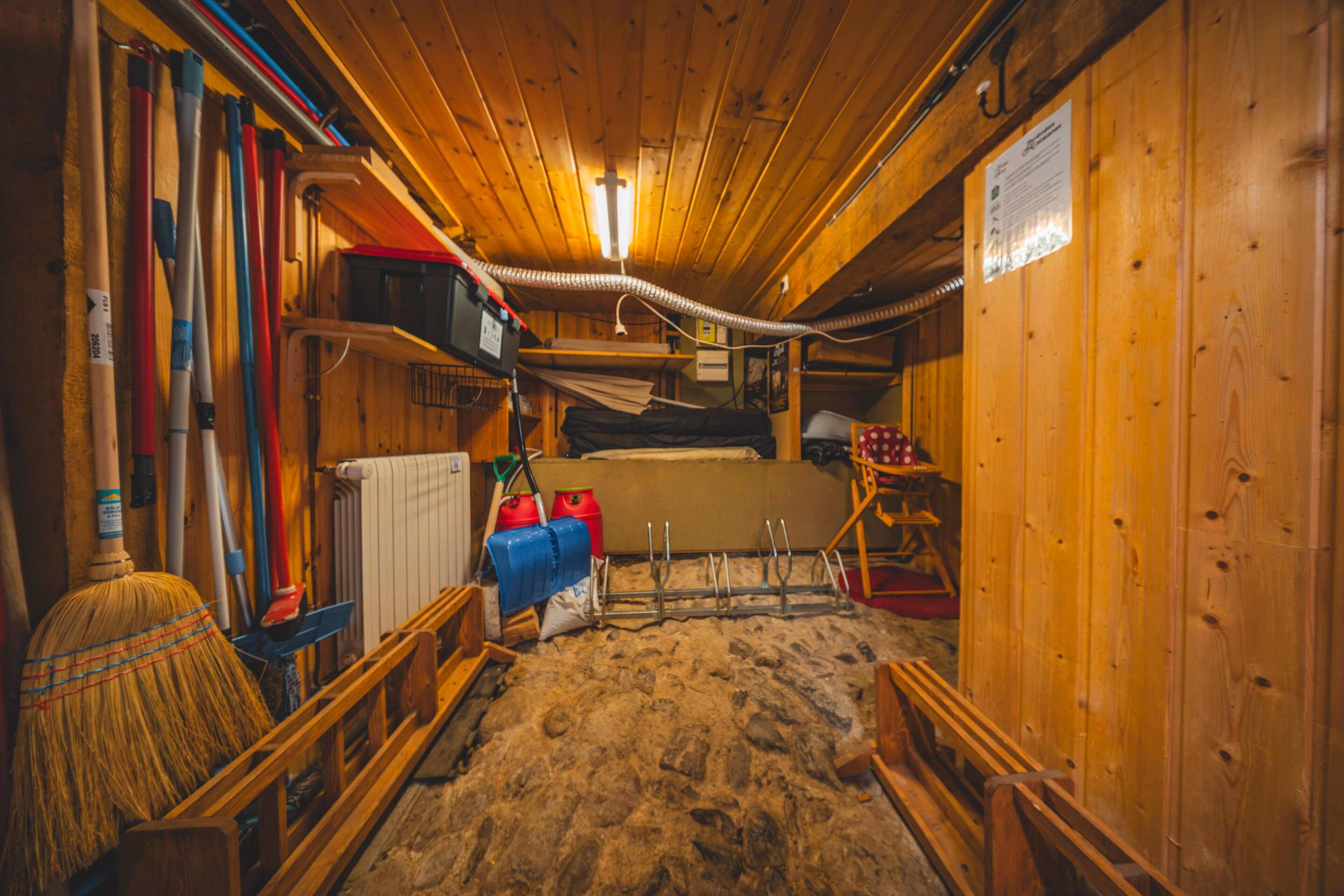 A cabin interior with a bunk bed, a broom, a radiator, and various tools.