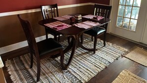 A dining room with a wooden table, four chairs, and a patterned rug. - Serenity Haus centrally-located townhome only .2 of a mile from downtown.. (Helen)