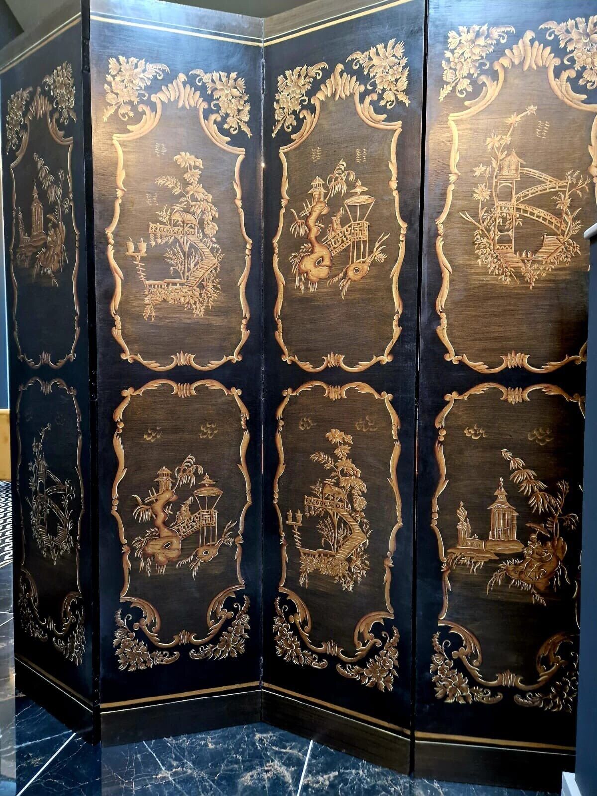 A four-panel folding screen with intricate carvings of traditional buildings and nature scenes.