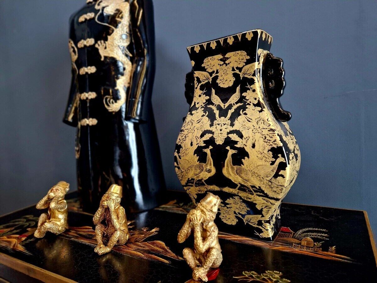 A display of black and gold decorative items, including a vase and figurines, on a dark surface.