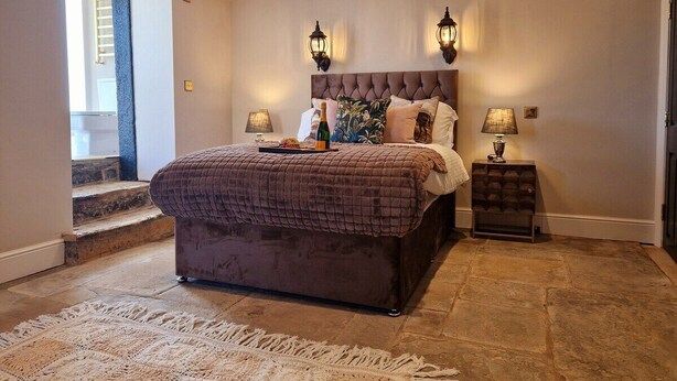 A bedroom with a large bed, two bedside lamps, a nightstand, and a view of a staircase. - The Hamilton luxury apartments-Lord William suite (Cabus)